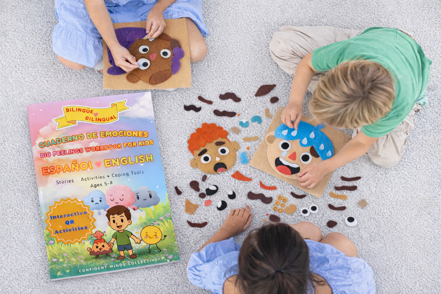 Children playing with emotion face cards on a floor with a book titled 'Emotions' in Spanish and English.